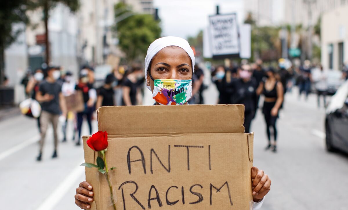 A woman holds a sign that says "Anti Racism. 