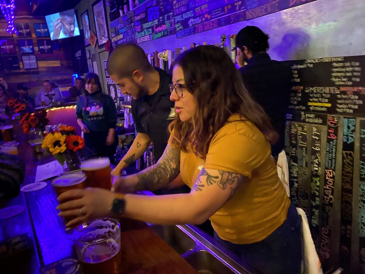 Bartender Joann Cornejo serves two craft beers at Machete Beer House in National City on Dec. 19. The establishment held an event for Insurgente, a brewery facing shut-down in Tijuana.