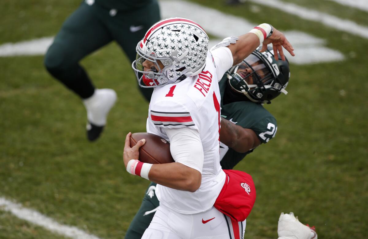 Ohio State quarterback Justin Fields pushes away Michigan State cornerback Shakur Brown.