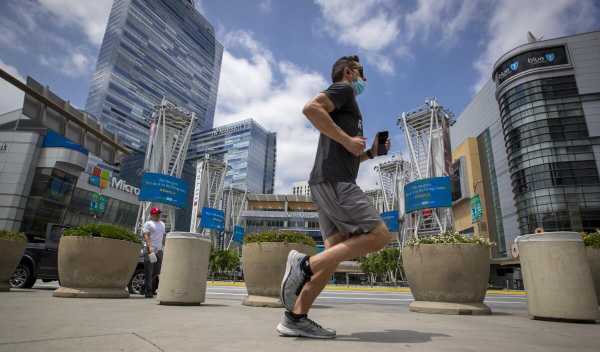 A jogger wears a protective mask while passing LA Live