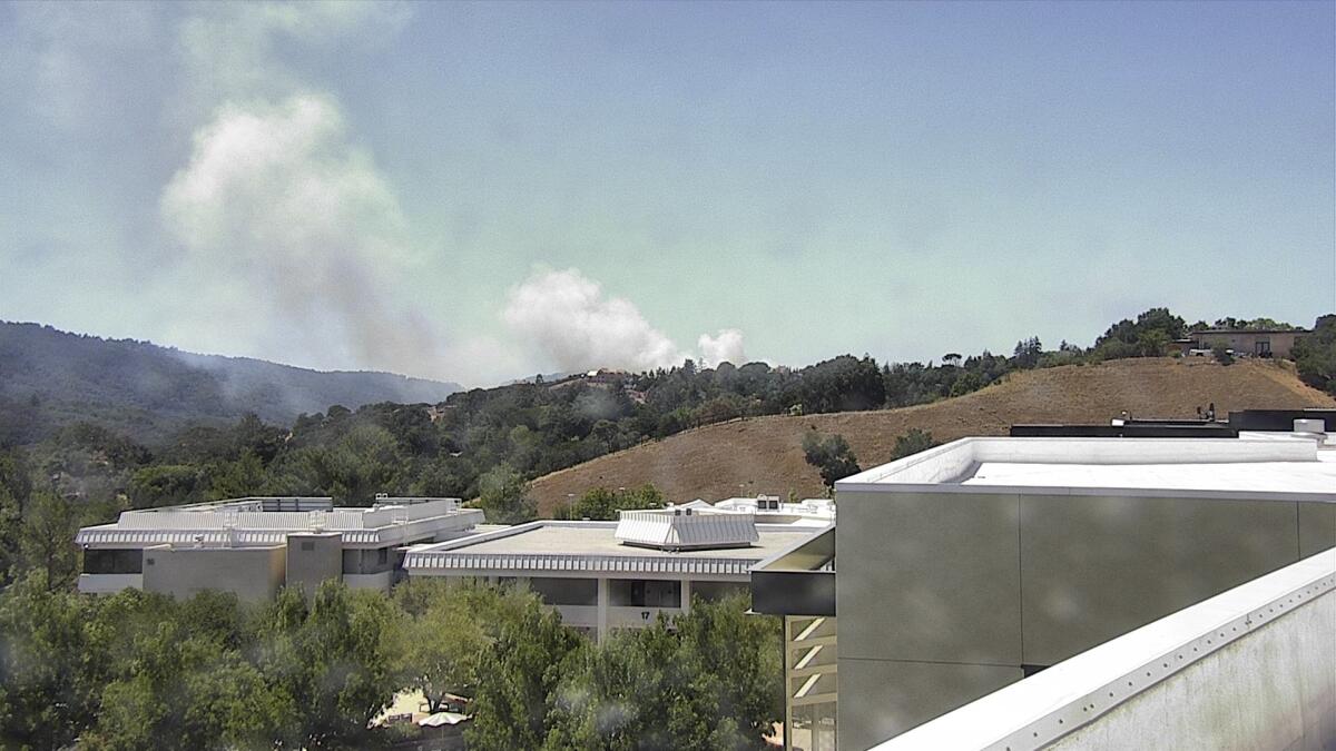 Smoke from a wildfire billows behind buildings in San Mateo County.