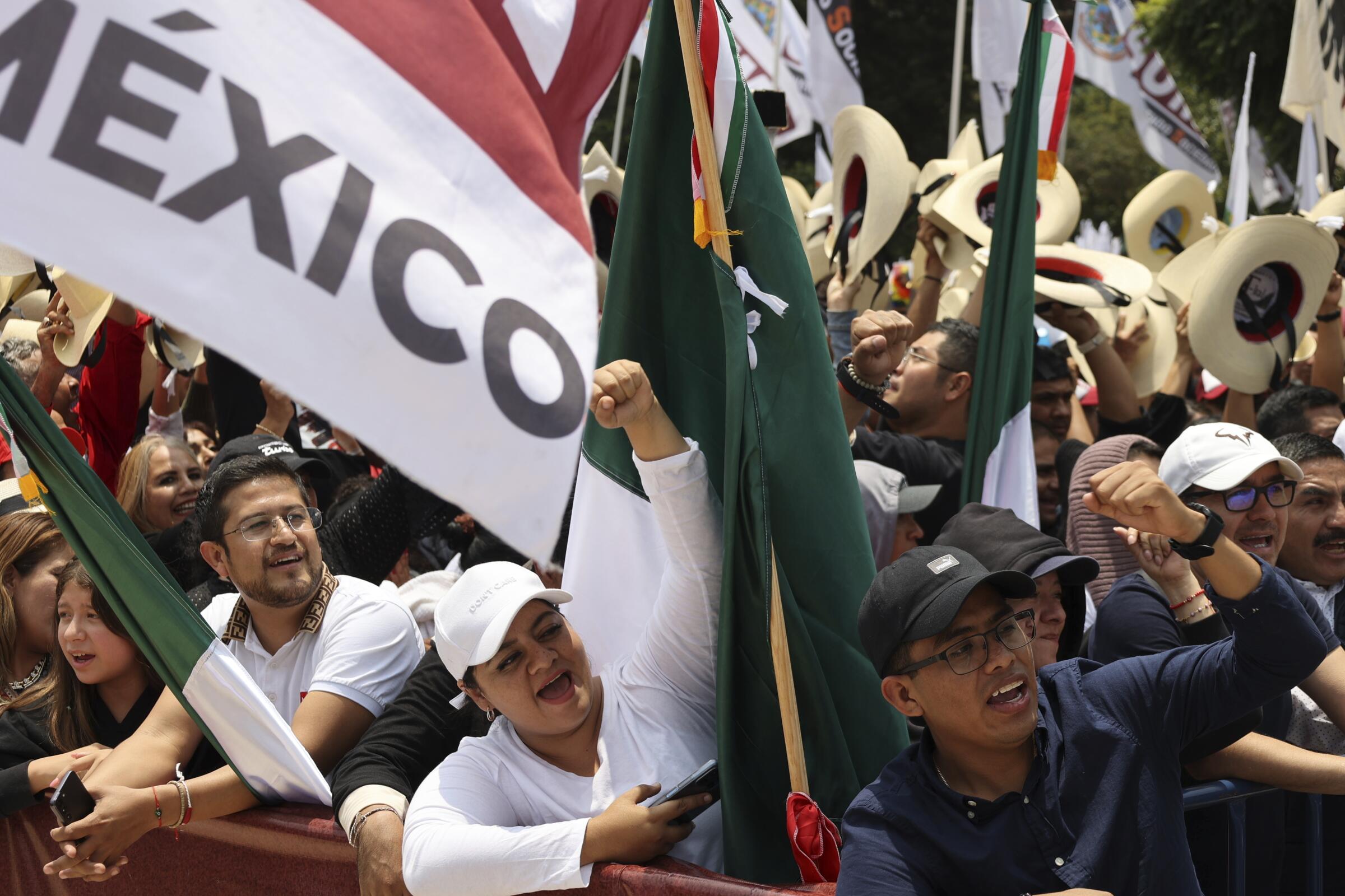 People cheer and hold Mexican flags at a rally.
