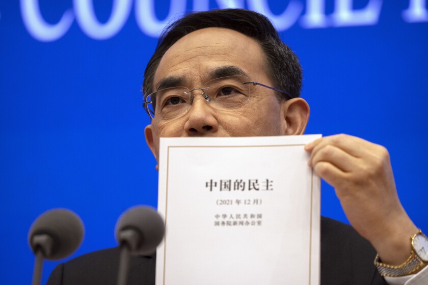 Xu Lin, viceministro del Departamento de Publicidad del Comité Central del Partido Comunista de China, muestra una copia del reporte "Democracia que funciona", elaborado por el gobierno, durante una conferencia de prensa en Beijing, el 4 de diciembre de 2021. (AP Foto/Mark Schiefelbein)