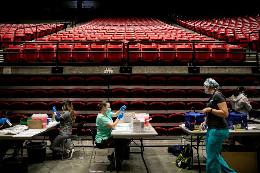 SAN DIEGO, CA - MARCH 23: Resident Nurse Jasmine Bombart fills a dose of the Pfizer Covid-19 vaccine at Viejas Arena at San Diego State University on Tuesday, March 23, 2021 in San Diego, CA. Tuesday was the first day that the new site was opened, on the floor of the arena that typically hosts basketball games, concerts and graduations. (Sam Hodgson / The San Diego Union-Tribune)