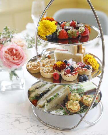 A three-tiered tower of finger sandwiches and other treats graces a table at the tea room of the Huntington in San Marino.