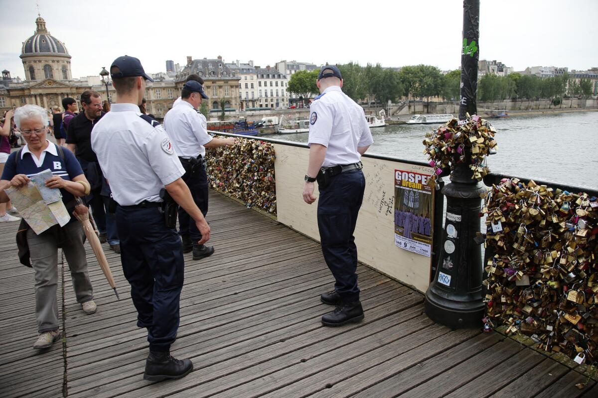 French police officers check out a repaired section of the Pont des Arts bridge after a chunk of fencing with thousands of locks fell off in Paris.