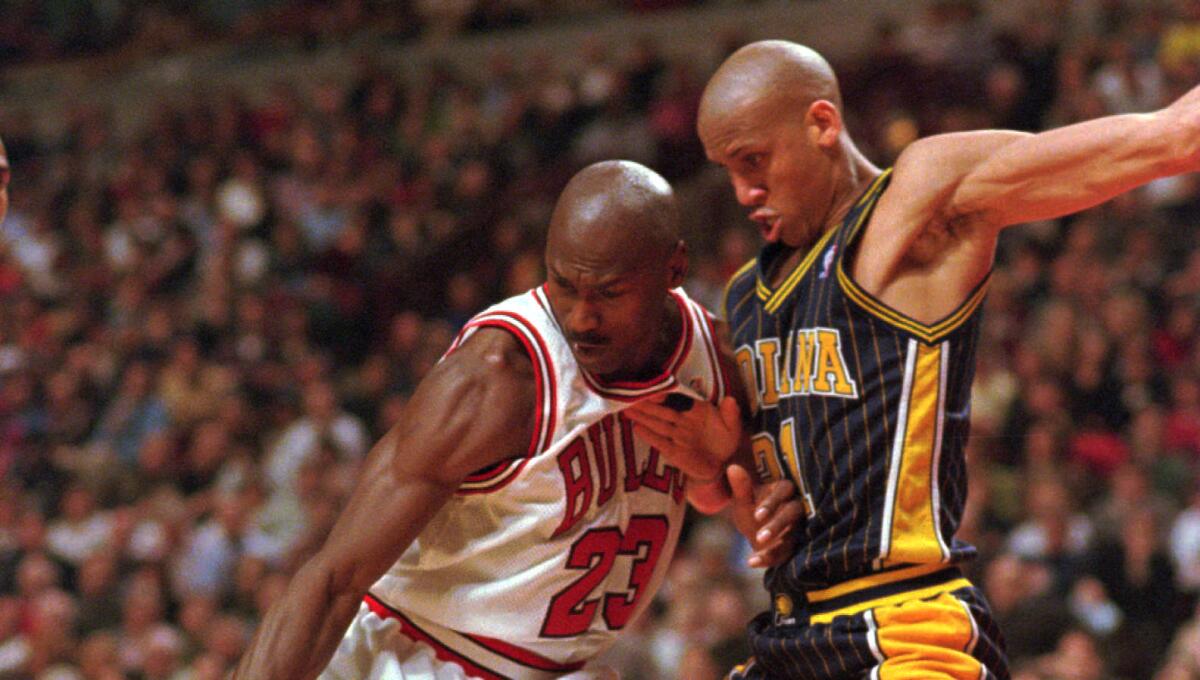 Bulls star Michael Jordan tries to keep control of the ball in front of Pacers standout Reggie Miller during a game in February 1998.