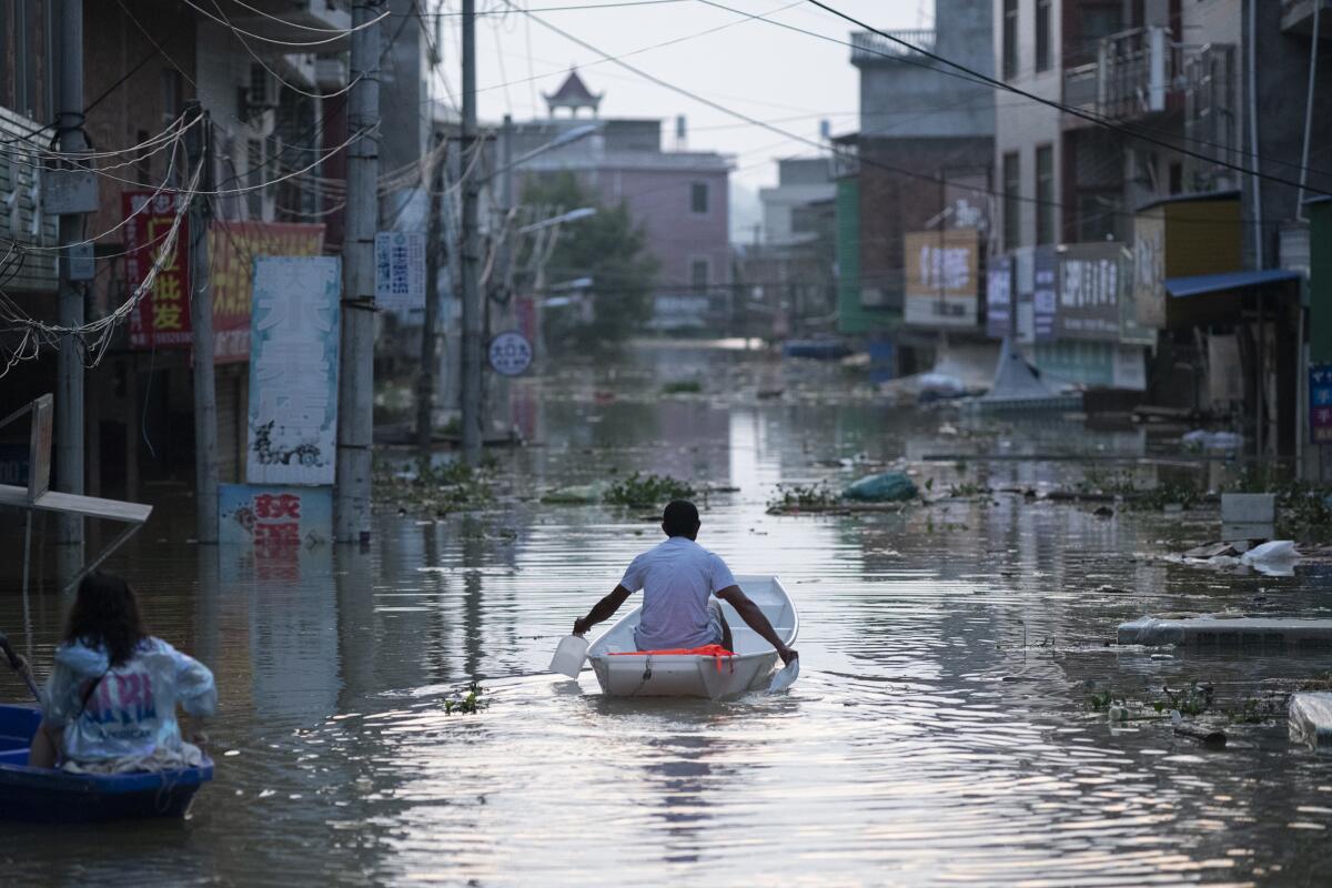 A man paddles a boat down a flooded street 