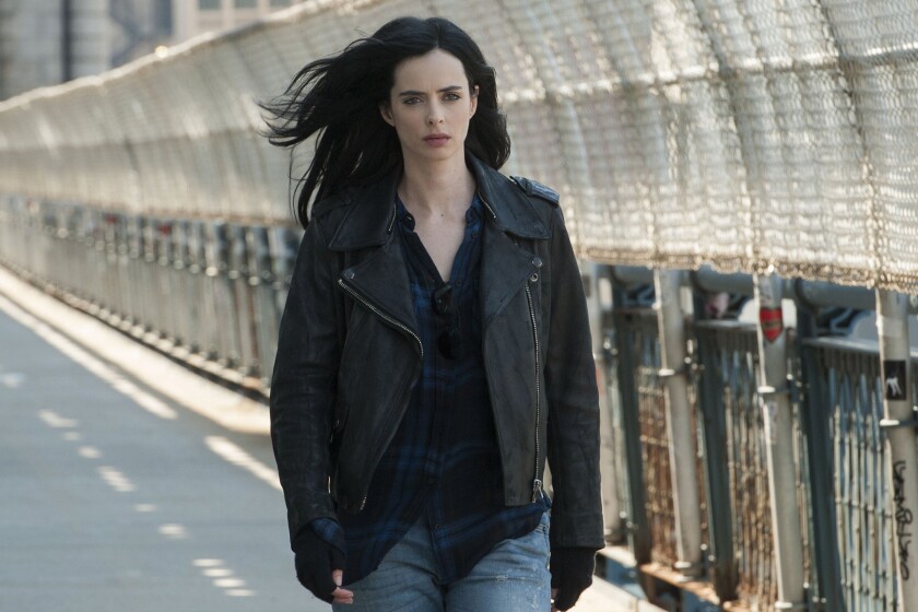 A woman wearing a black motorcycle jacket walks along a street