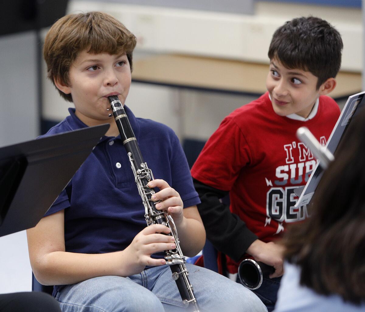 Nicholas Rogers, under the watchful eyes of fellow clarinetist Alex Paranyan, demonstrates a problem he is having with his clarinet at the Caesura Youth Orchestra rehearsal at Cerritos Elementary School in Glendale on Tuesday. A fundraiser for the music program will be held at a performance called "A Portrait of Fall" at the Glendale City Church on Sunday at 4 p.m.