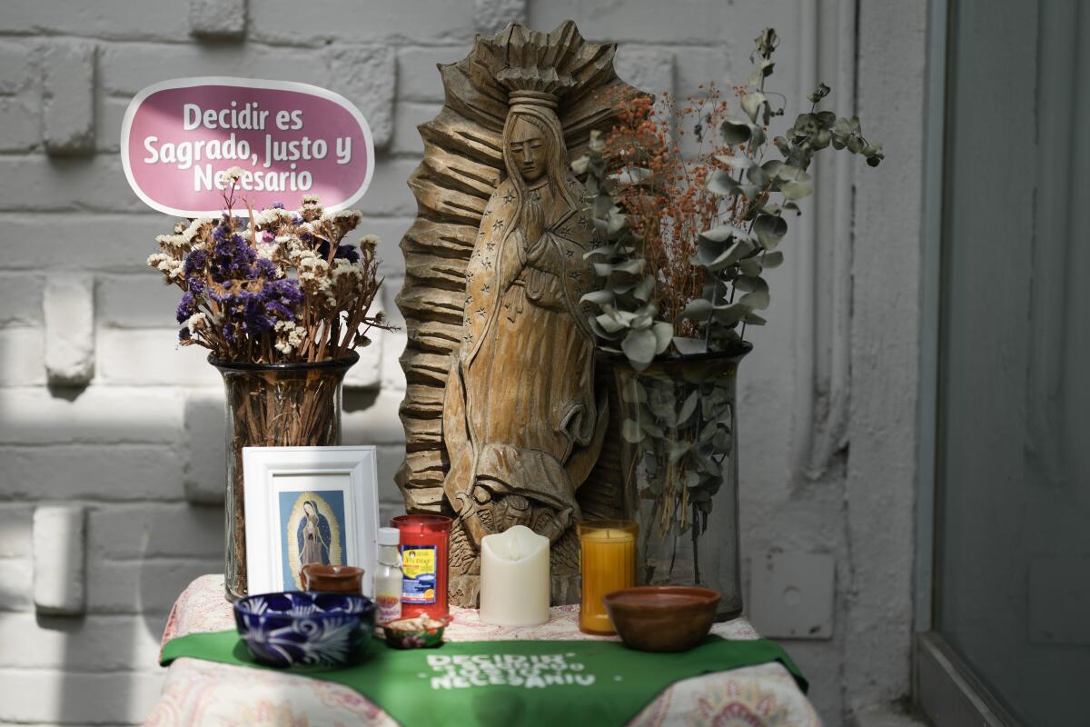 Un pañuelo verde y un cartel con un mensaje a favor del aborto adornan un altar 