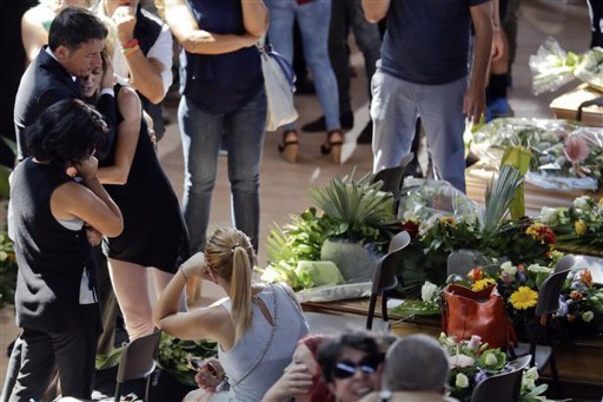 El primer ministro italiano Matteo Renzi, izquierda, conforta a una mujer al final de un funeral de estado para algunas de las víctimas del terremoto que sacudió el centro de Italia el mércoles, en Ascoli PIceno el sábado, 27 de agosto del 2016.