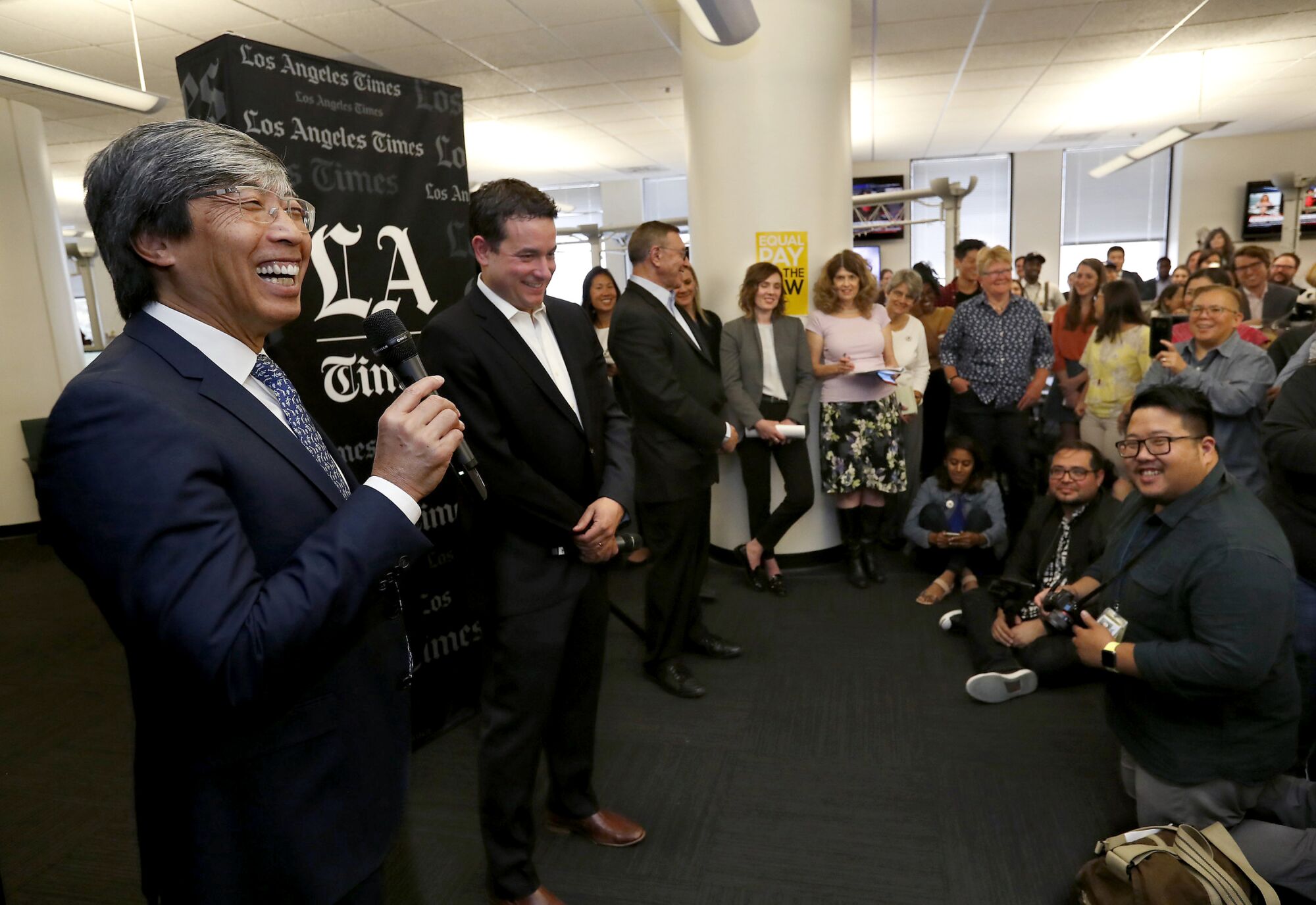 Dr. Patrick Soon-Shiong smiles as he speaks into a microphone in the Los Angeles Times newsroom