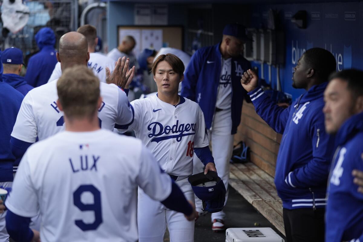 Dodgers pitcher Yoshinobu Yamamoto is greeted by teammates in the dugout after the top of the first inning 