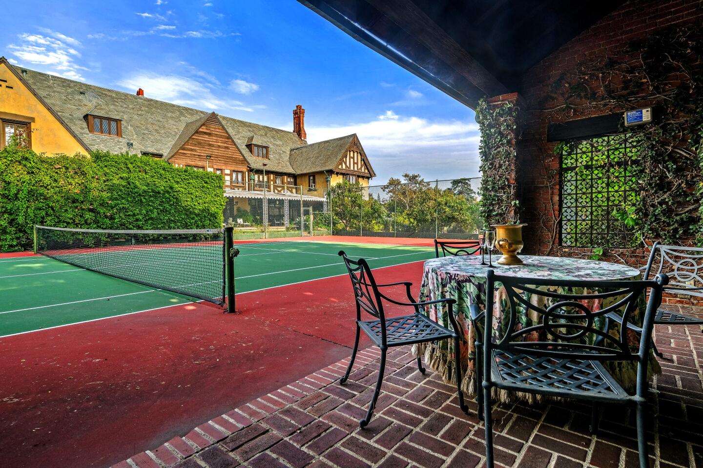 Metal patio furniture on a brick patio next to a tennis court