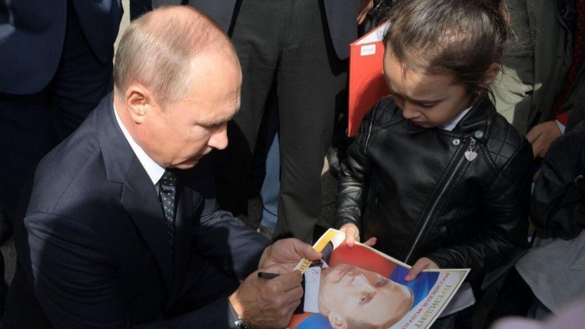 Russian President Vladimir Putin signs an autograph for a girl while meeting with residents in the Siberian city of Omsk on Tuesday.