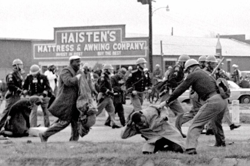Alabama state troopers swing nightsticks to break up the "Bloody Sunday" voting march in Selma, Ala., on March 7, 1965. John Lewis, front right, of the Student Non-violent Coordinating Committee, is put on the ground by a trooper.
