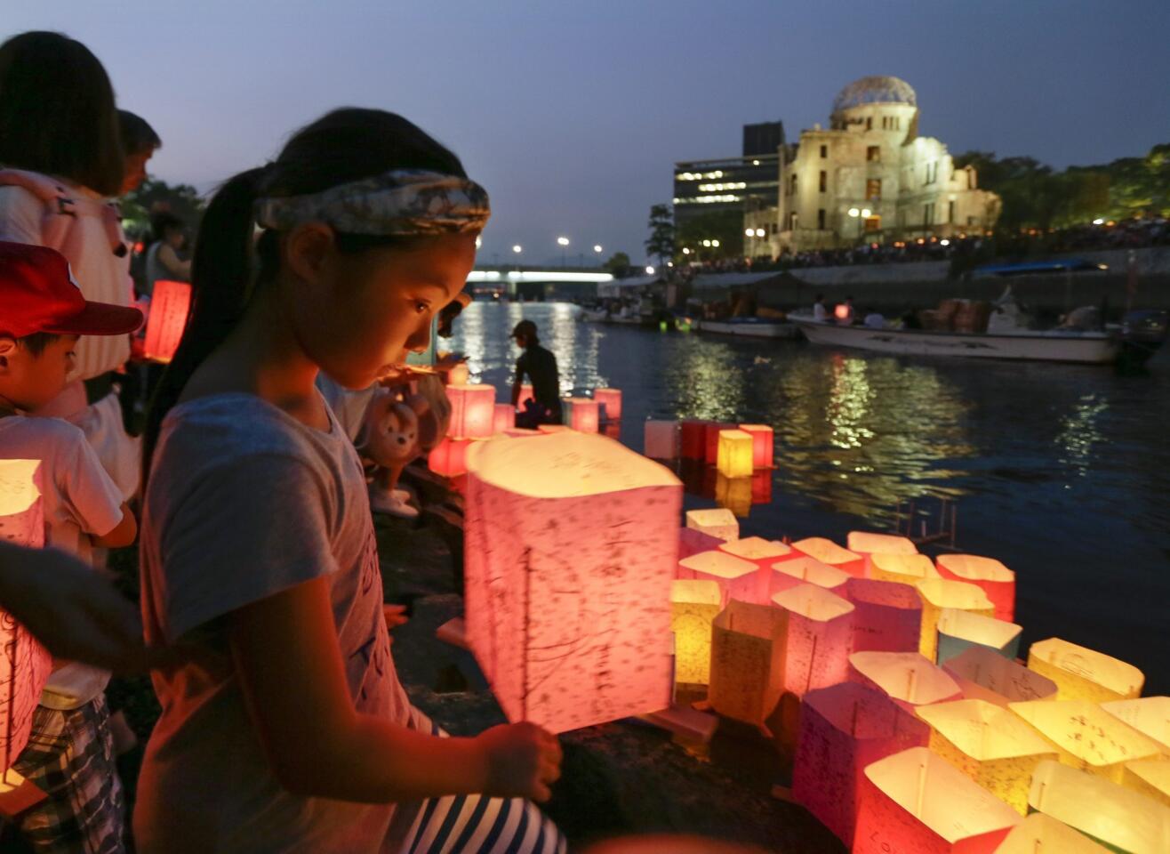 A girl floats a paper lantern on the Motoyasu River to comfort souls of victims killed by the atomic bombing, past the Atomic Bomb Dome at Hiroshima Peace Memorial Peace Park in western Japan.