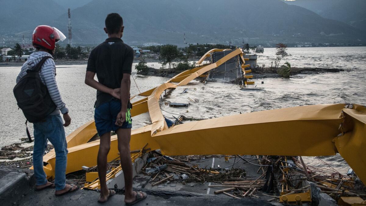 People observe wreckage Monday after the tsunami that killed at least 1,200 people in Palu, Indonesia.