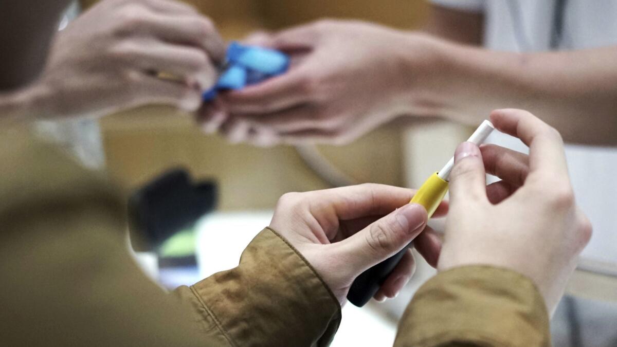 Visitors try out IQOS, Philip Morris' pen-like "heat-not-burn" tobacco device, at a store in Tokyo. The devices are touted as safer than conventional cigarettes, but a new analysis of company data raises doubts about that claim.