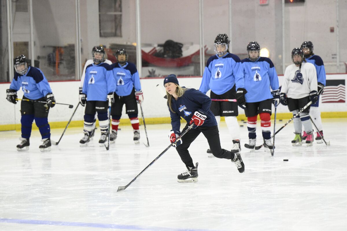 FILE - United States hockey player Haley Skarupa, front, demonstrates a drill during a hockey clinic presented by the Washington Capitals and the Professional Women's Hockey Players Association, Friday, March 4, 2022, in Arlington, Va. The Professional Women’s Hockey Players Association has decided to break off talks with the rival Premier Hockey Federation, the latest blow in a widening rift between two factions that contend they want to grow the sport in North America. The PWHPA executive board voted unanimously to end discussions with the PHF about collaborating, a person with knowledge of the situation told The Associated Press. The person spoke on condition of anonymity late Monday, April 11, 2022, because the decision had not been announced. (AP Photo/Nick Wass, File)