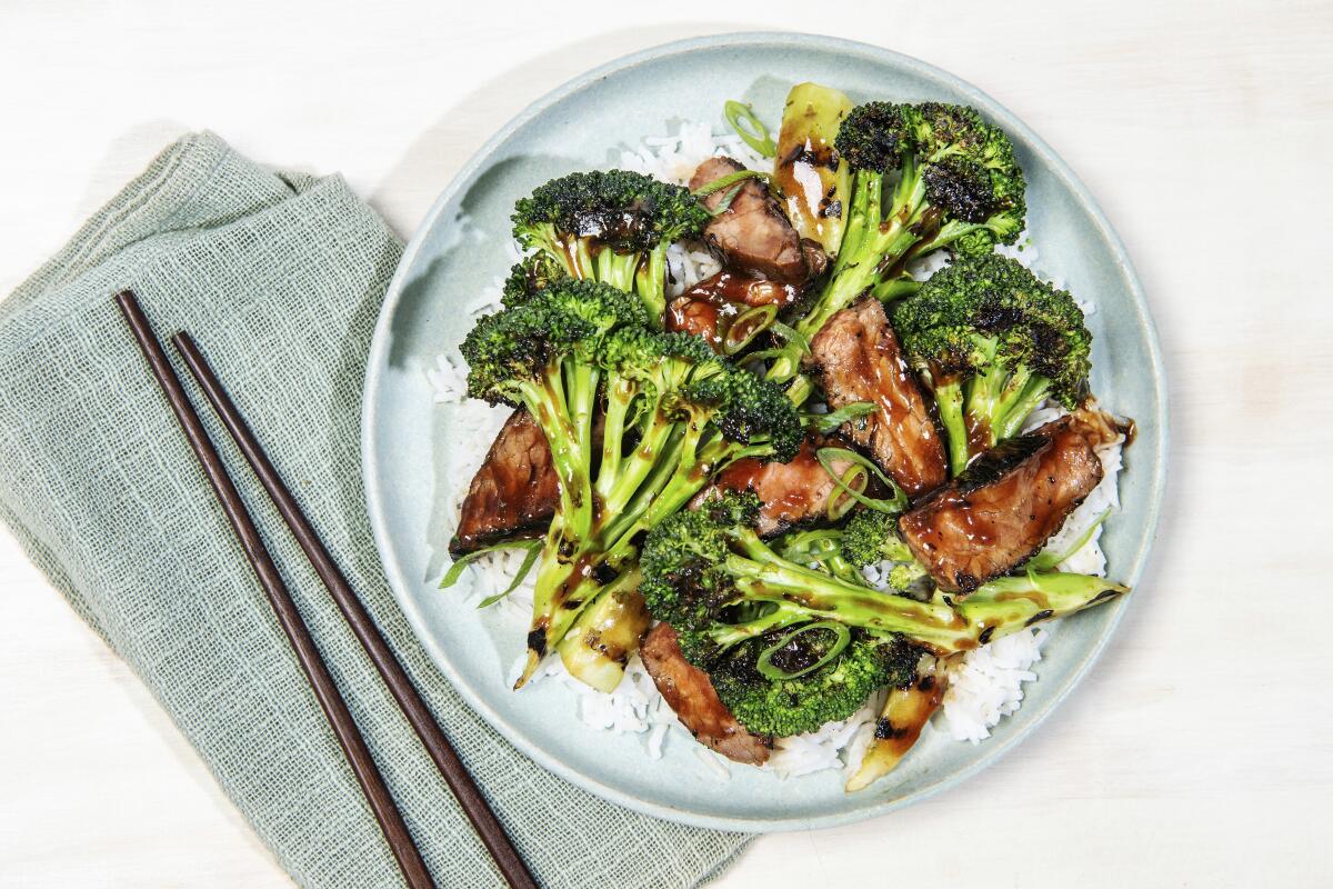 A plate of grilled broccoli and beef that has more vegetable than meat.