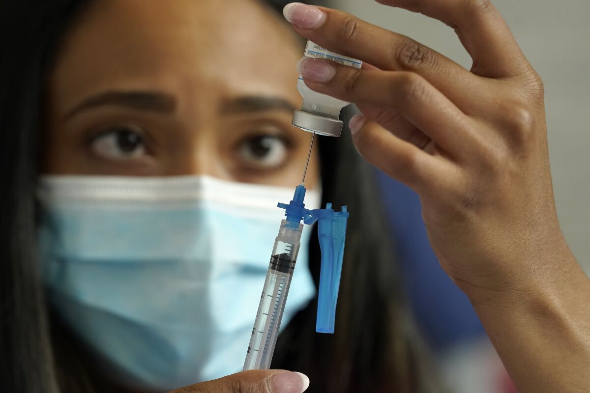 In this May 2021 photo, a nurse draws a Moderna COVID-19 vaccine into a syringe at a vaccination clinic in Foxborough, Mass. 