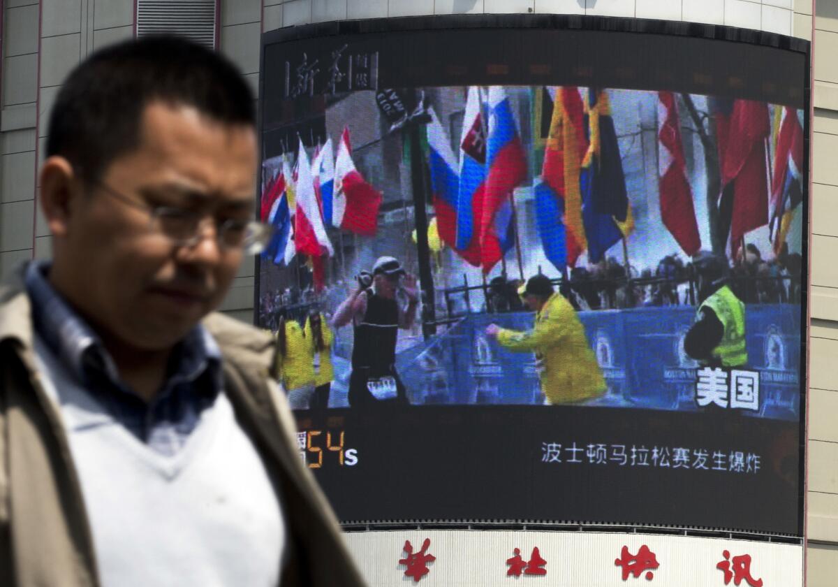 A Chinese man in Beijing walks past a huge screen reporting on the Boston Marathon bombings. One of the three people killed has been identified as a Chinese national studying in the U.S.