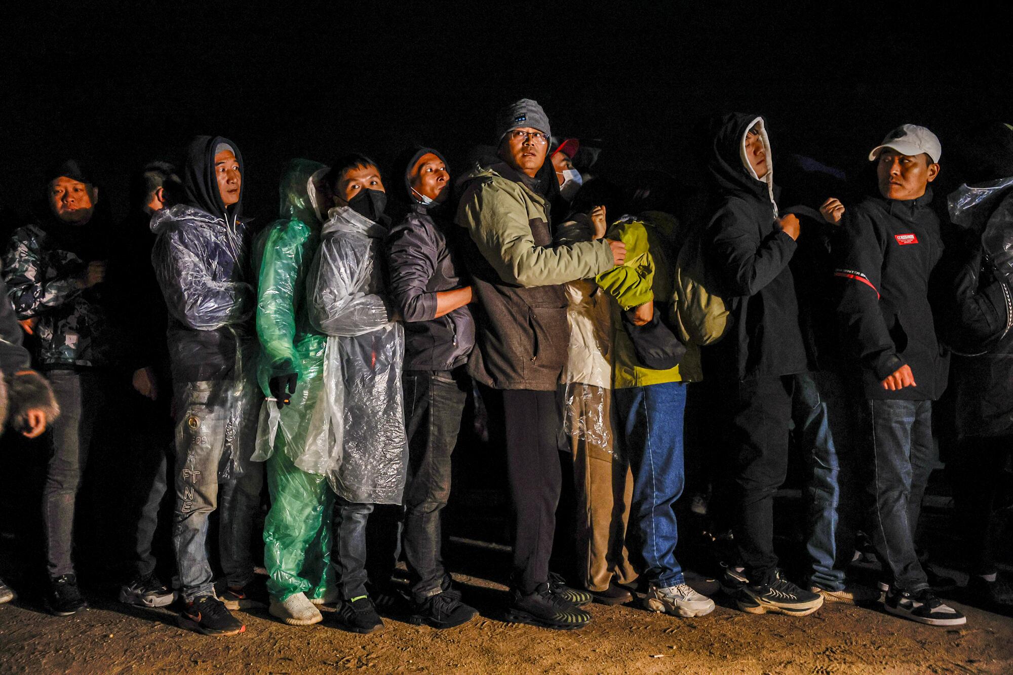 Asylum seekers line up to receive wristbands from a U.S. Border 