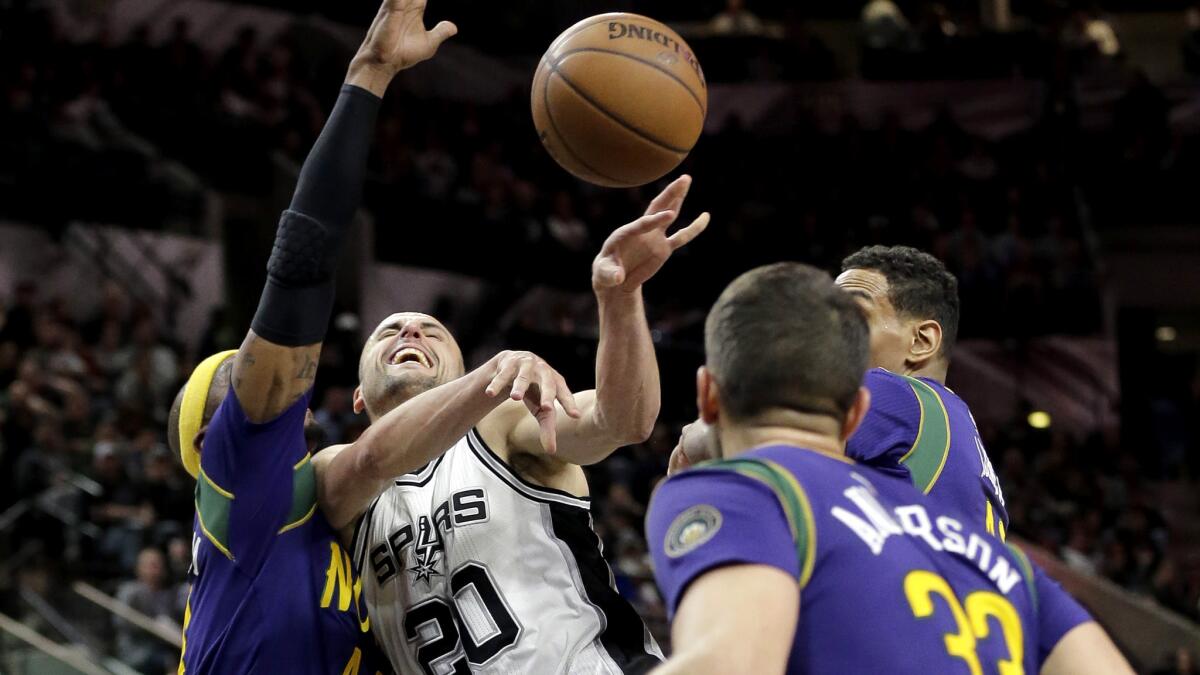 Spurs guard Manu Ginobili (20) is fouled by elicans forward Dante Cunningham, left, while driving to the basket during their game Wednesday.
