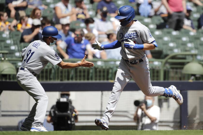 Los Angeles Dodgers' AJ Pollock is congratulated by third base coach Dino Ebel after hitting a home run.