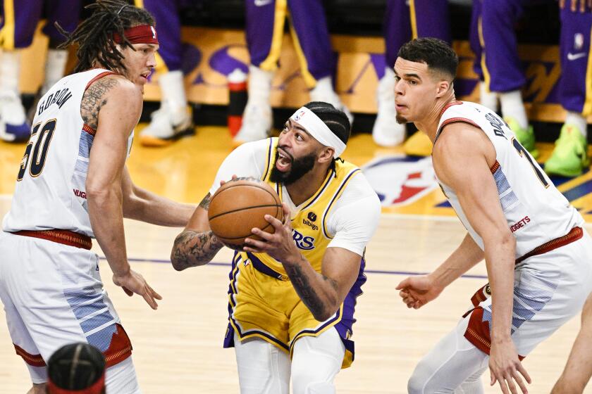 LOS ANGELES, CA - MAY 22: Los Angeles Lakers forward Anthony Davis, center, goes up for a shot between Denver Nuggets forward Aaron Gordon, left, and forward Michael Porter Jr. during the first quarter of game four in the NBA Playoffs Western Conference Finals at Crypto.com Arena on Monday, May 22, 2023 in Los Angeles, CA. (Gina Ferazzi / Los Angeles Times)