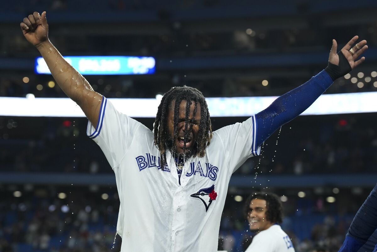 Toronto Blue Jays' Vladimir Guerrero Jr. raises his arms after being doused following the team's win over the Baltimore Orioles in 10 innings in a baseball game Wednesday, June 15, 2022, in Toronto. Guerrero drove in the winning run. (Nathan Denette/The Canadian Press via AP)