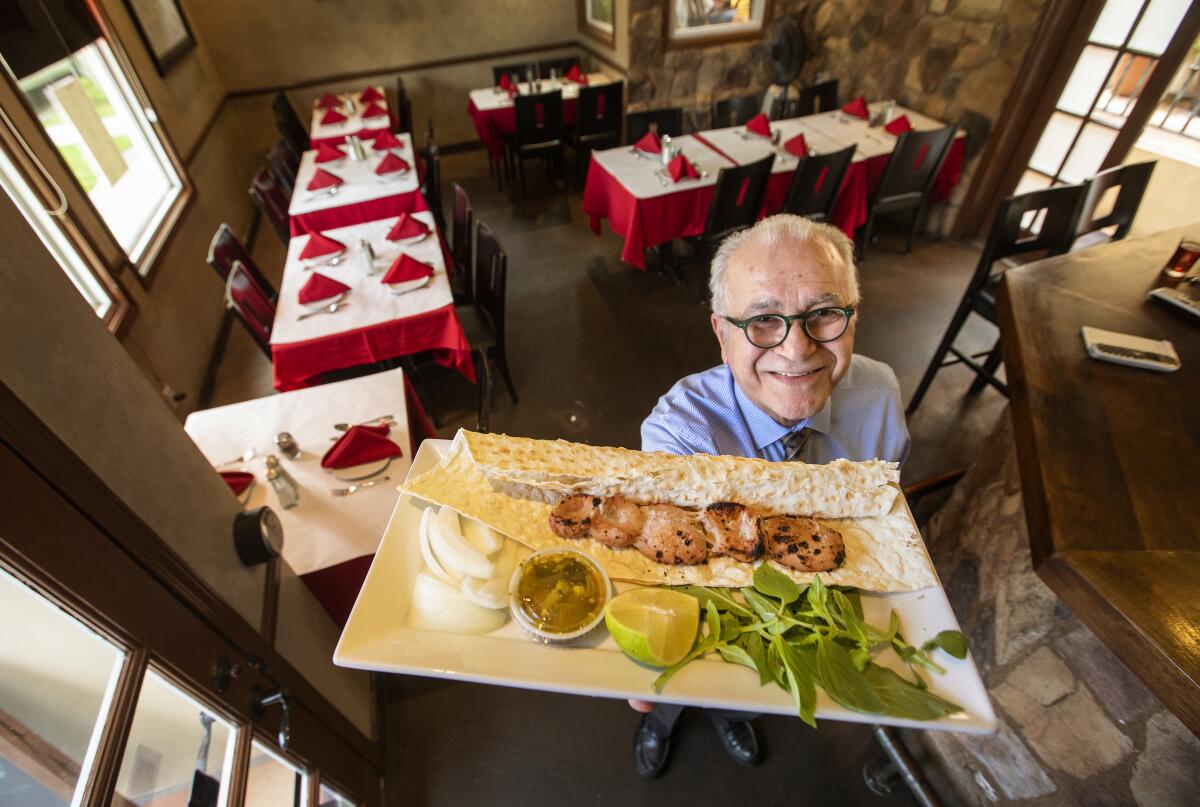 Farhad Pourbastani, manager at Attari Grill, holds up a plate featuring donbalan, grilled lamb testicle. "It's amazing to be eating this dish in L.A.," said Anissa Helou.