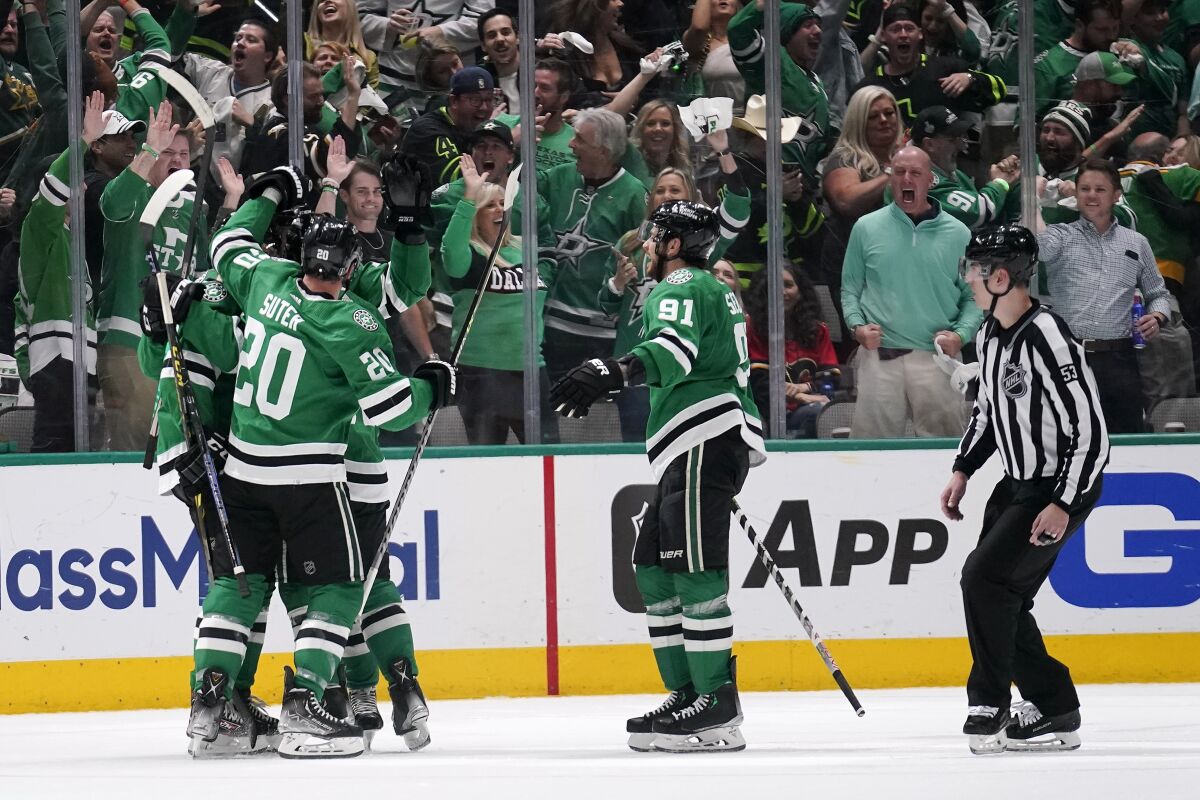 Dallas Stars players celebrate a goal by Miro Heiskanen during the second period of Game 6 of an NHL hockey Stanley Cup first-round playoff series against the Calgary Flames, Friday, May 13, 2022, in Dallas. (AP Photo/Tony Gutierrez)