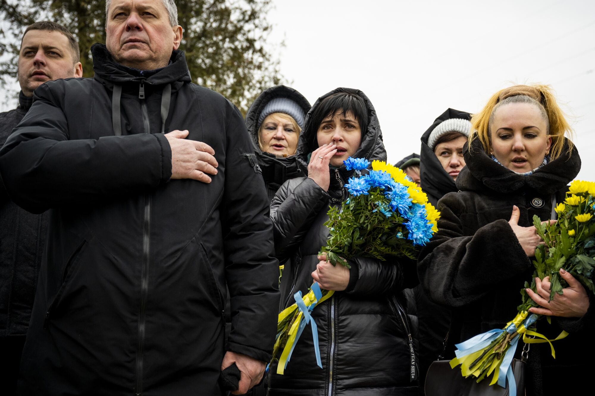 Люди стоят, прижав руки к сердцу на улице.