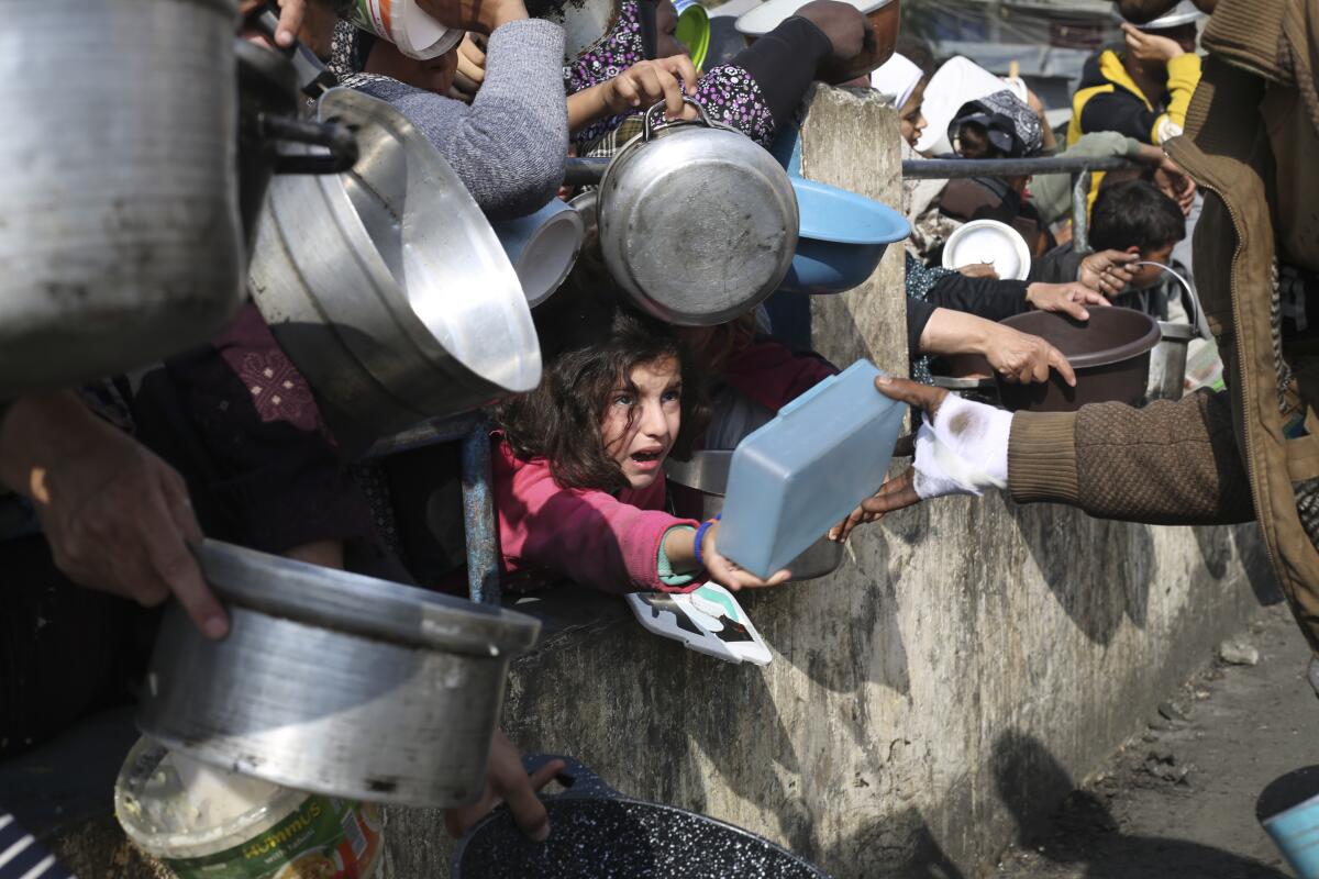 Palestinos hacen fila para conseguir comida durante la ofensiva aérea y terrestre en la Franja 