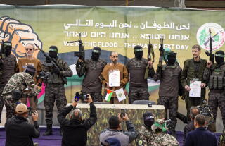 Israeli captiveswho have been held hostage by Hamas are escorted on a stage.