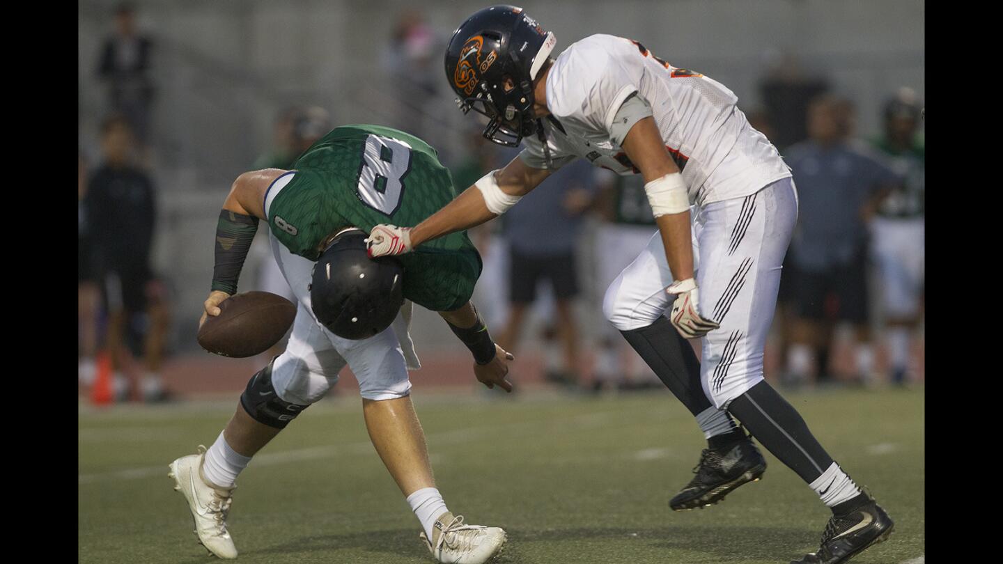 Los Amigos High's Joseph Garcia, right, tackles Fairmont Prep quarterback Kyle Karam during the first half in a nonleague game at Shapell Stadium in Yorba Linda on Thursday. (Kevin Chang/ Staff Photographer)
