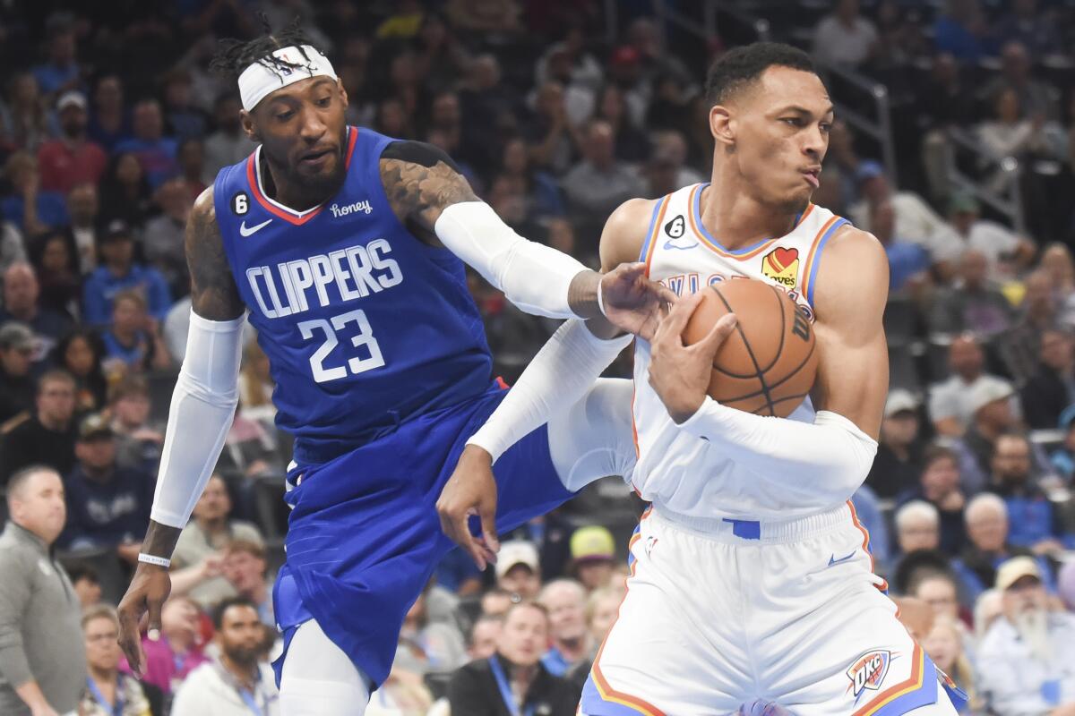 Clippers forward Robert Covington tries to get the ball away from Oklahoma City Thunder forward Darius Bazley.