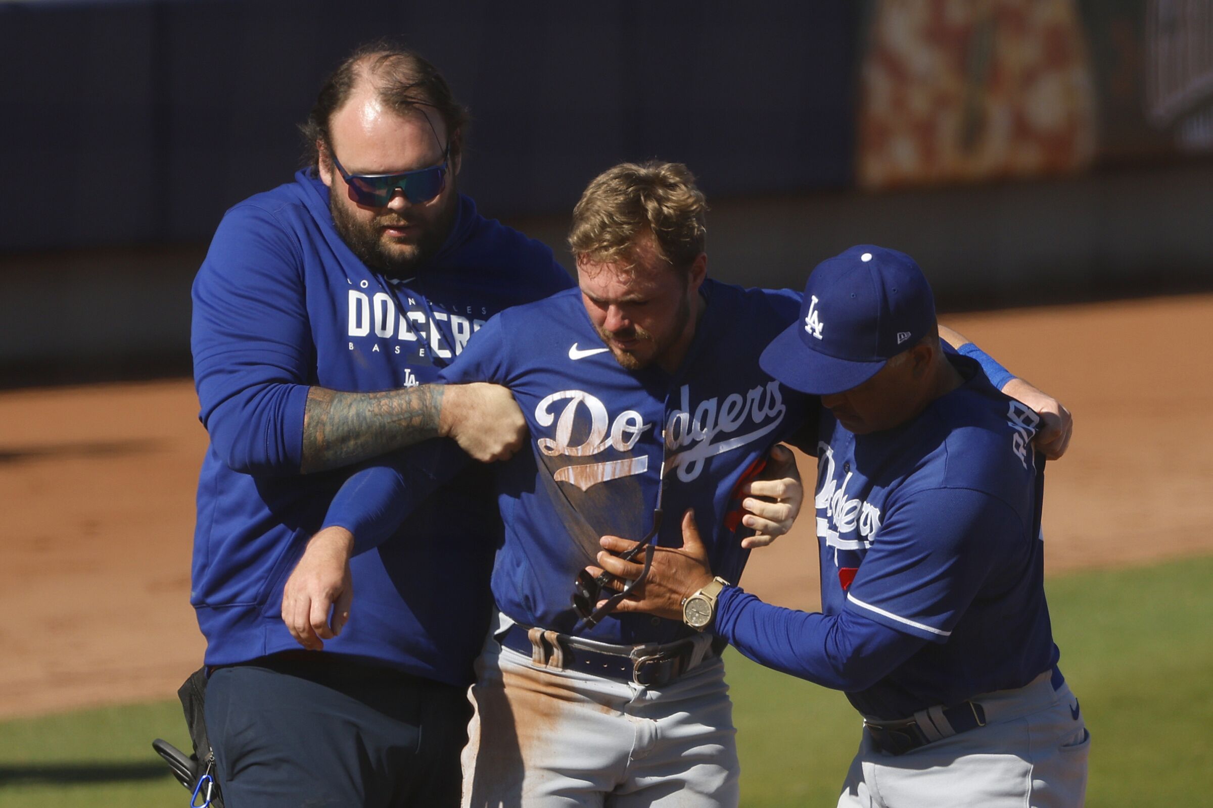 The Dodgers' Gavin Lux is loaded onto a cart with the help of a trainer and manager Dave Roberts after getting injured.