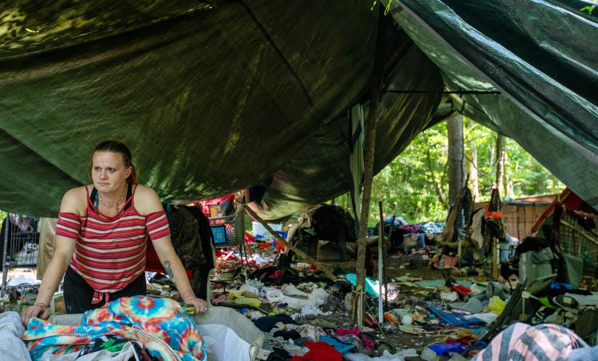 A woman sits in an encampment in the woods