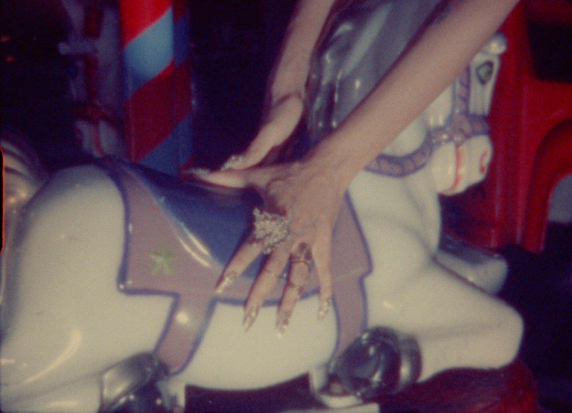 Hands on a merry-go-round horse in a film still.