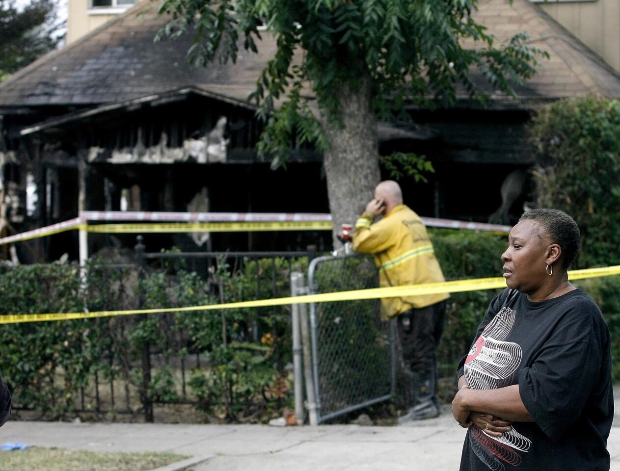 Pamela Clark, estranged wife of one of the two men who died in an early morning fire, stands near the gutted home on the 1300 block of El Sereno Avenue in Pasadena.