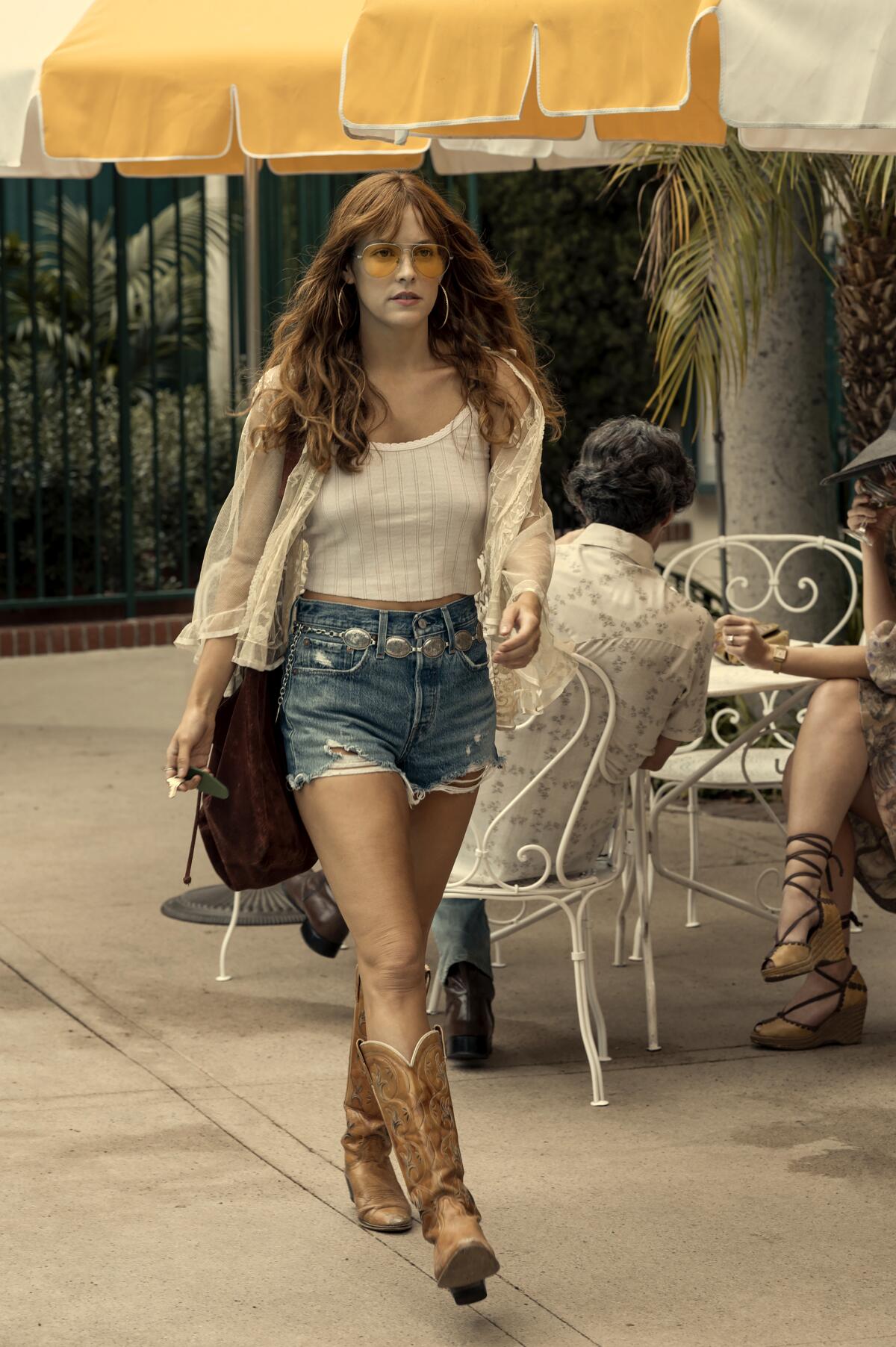 As Daisy Jones, Riley Keough wears denim shorts and boots.
