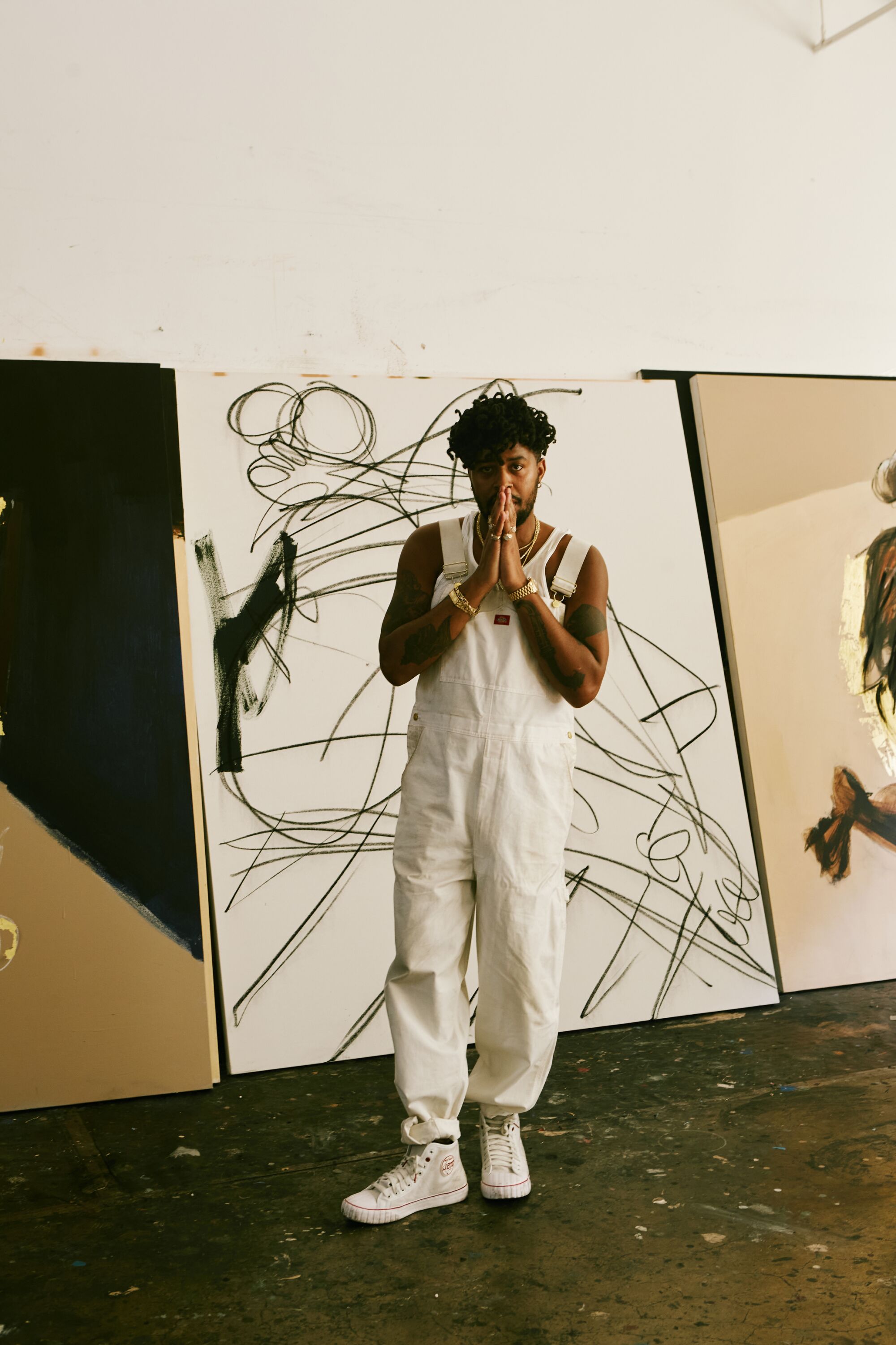 An artist in white coveralls stands in front of an artwork