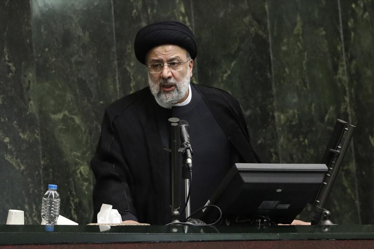 Iranian President Ebrahim Raisi speaks in front of a microphone