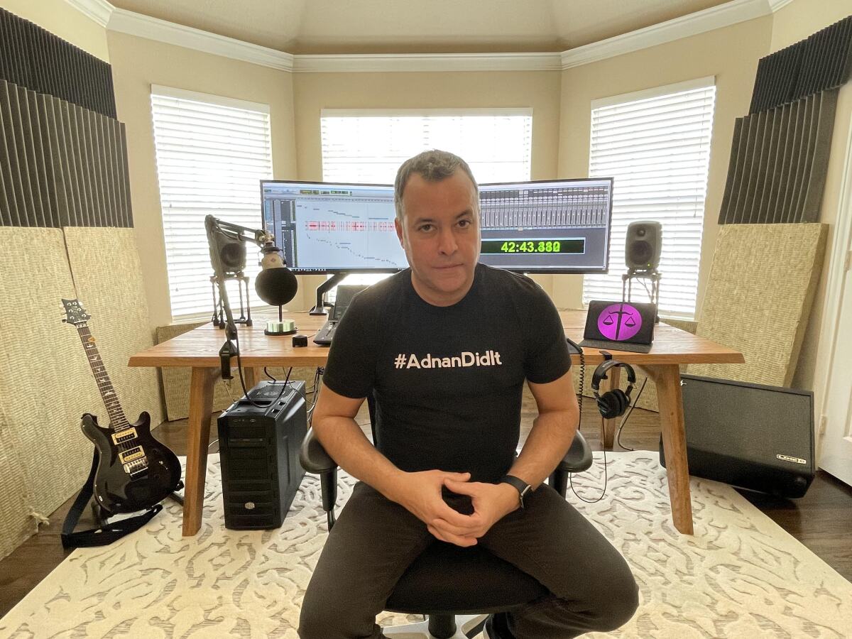 A man in a black shirt sits in a chair.