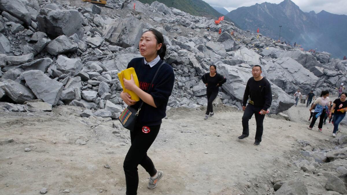 A woman brings paper offerings to the landslide site in Xinmo.