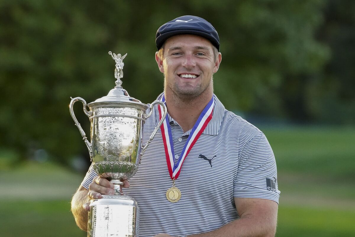 Bryson DeChambeau, of the United States, holds up the winner's trophy.